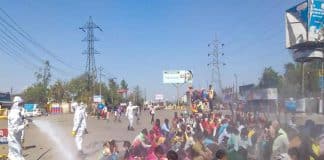 Trabalhadores indianos são forçados a permanecer no chão enquanto são pulverizados com desinfetantes usados ​​em ônibus